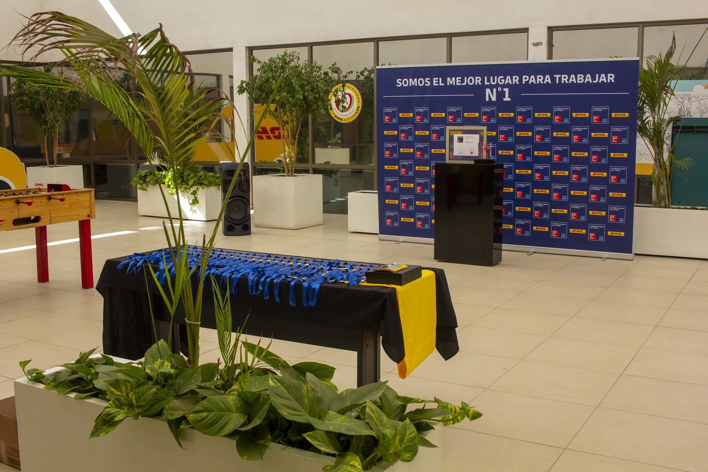 Montaje del evento Great Place to Work 2019 en DHL: fondo fotográfico, pedestal y mesa de medallas.