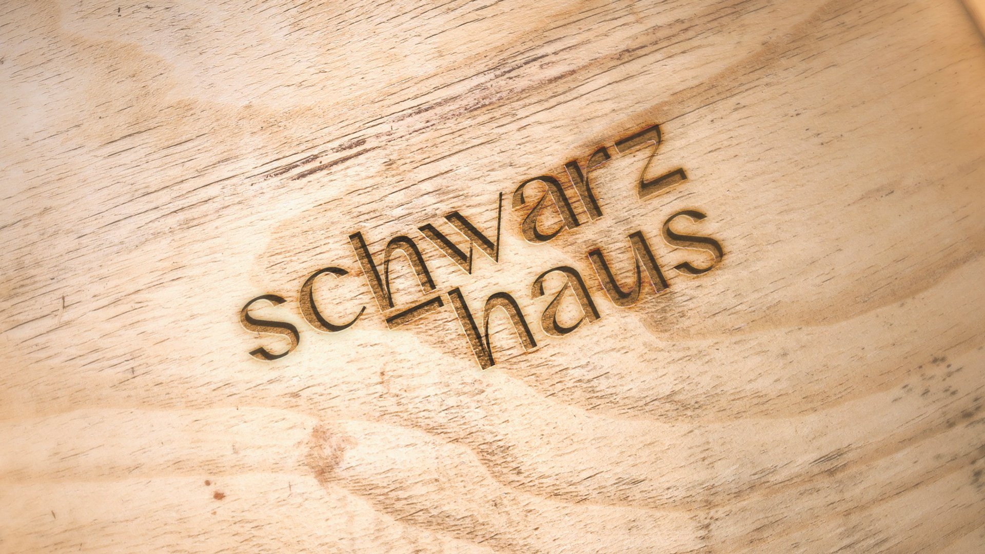 Logotipo de Schwarz-Haus grabado en una superficie de madera.