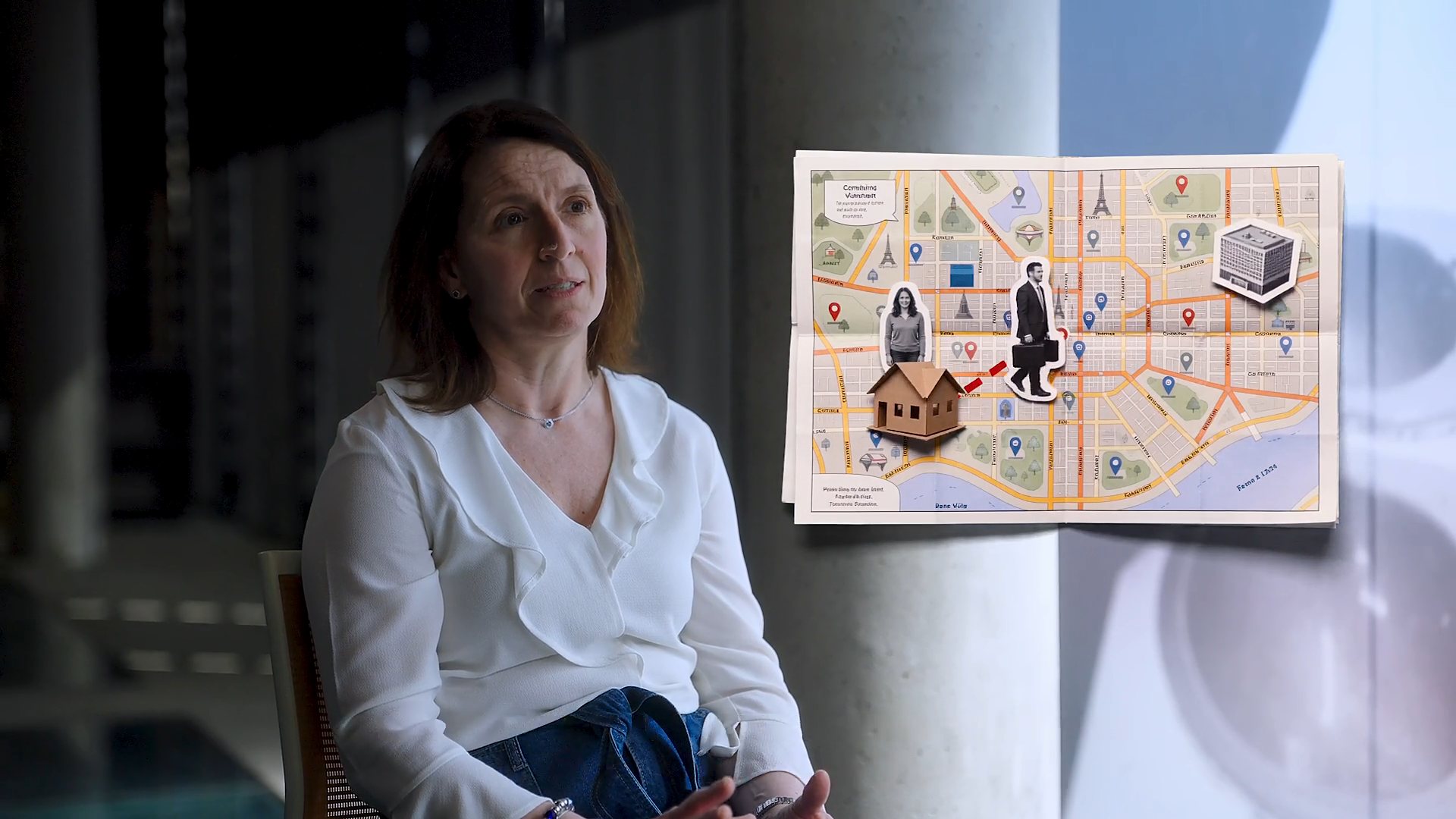 Marcela Perticará en penumbra, junto al plano de la ciudad en collage.