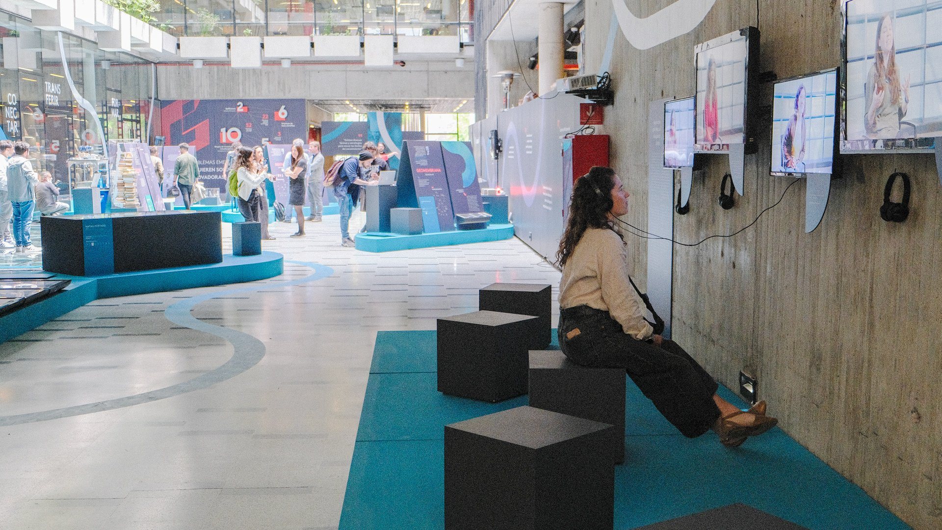 Una visitante escucha una cápsula con audífonos en la sala de la exposición.